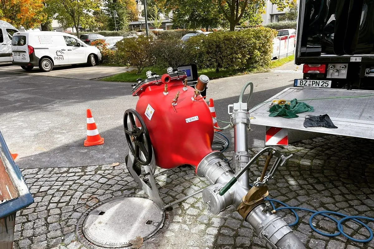 Geöffneter Schacht auf Kopfsteinpflaster mit Technik für den Einbau eines Schlauchliners